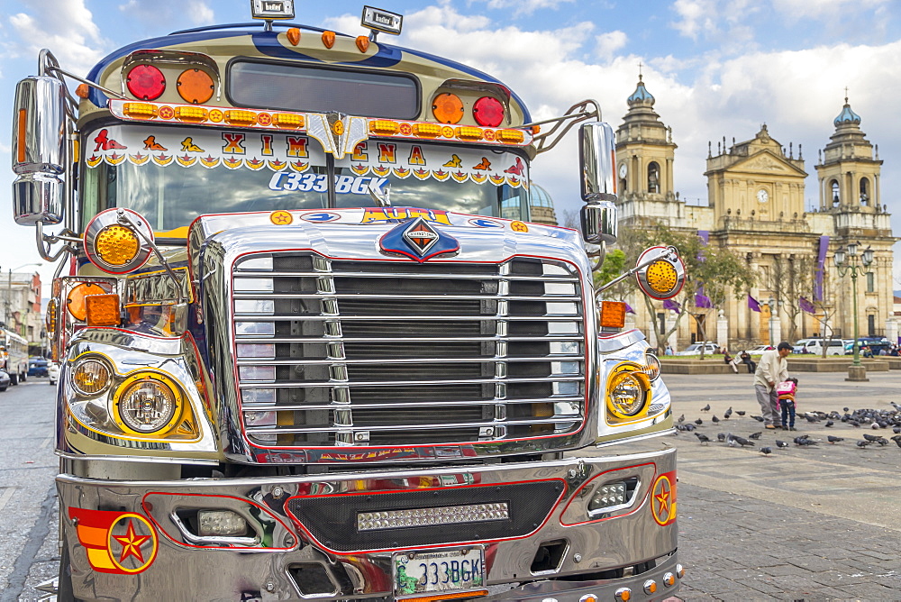 A typical chicken bus standing at the main square of Guatemala City with view to the Metropolitan Cathedral in the background, Guatemala City, Guatemala, Central America