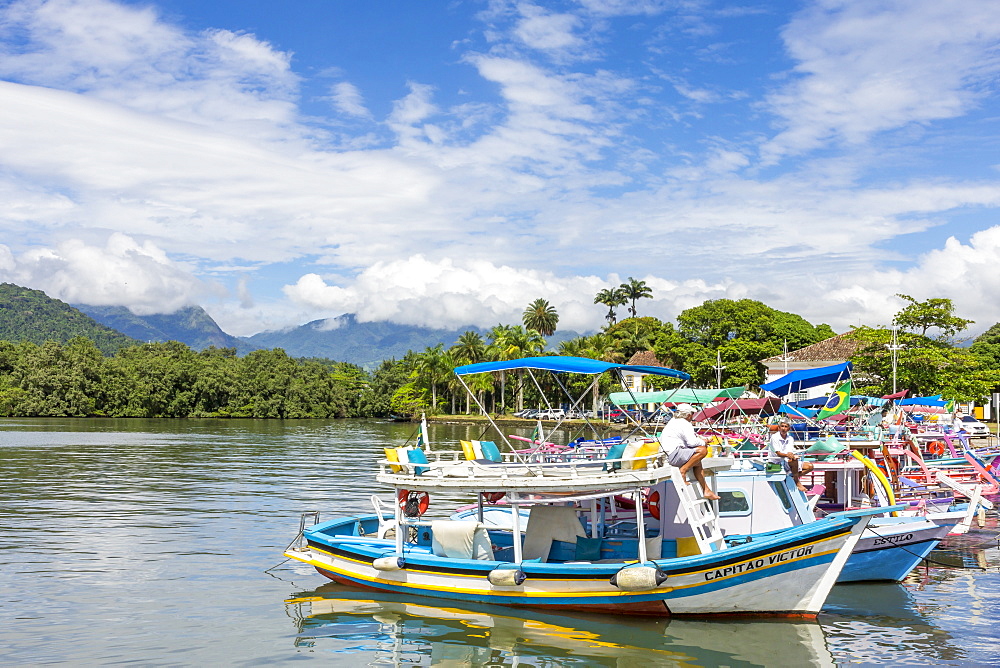 Colorful tour boats anchoring at the port of Paraty with view to the Serra da Bocaina mountain range, Rio de Janeiro, Brazil, South America