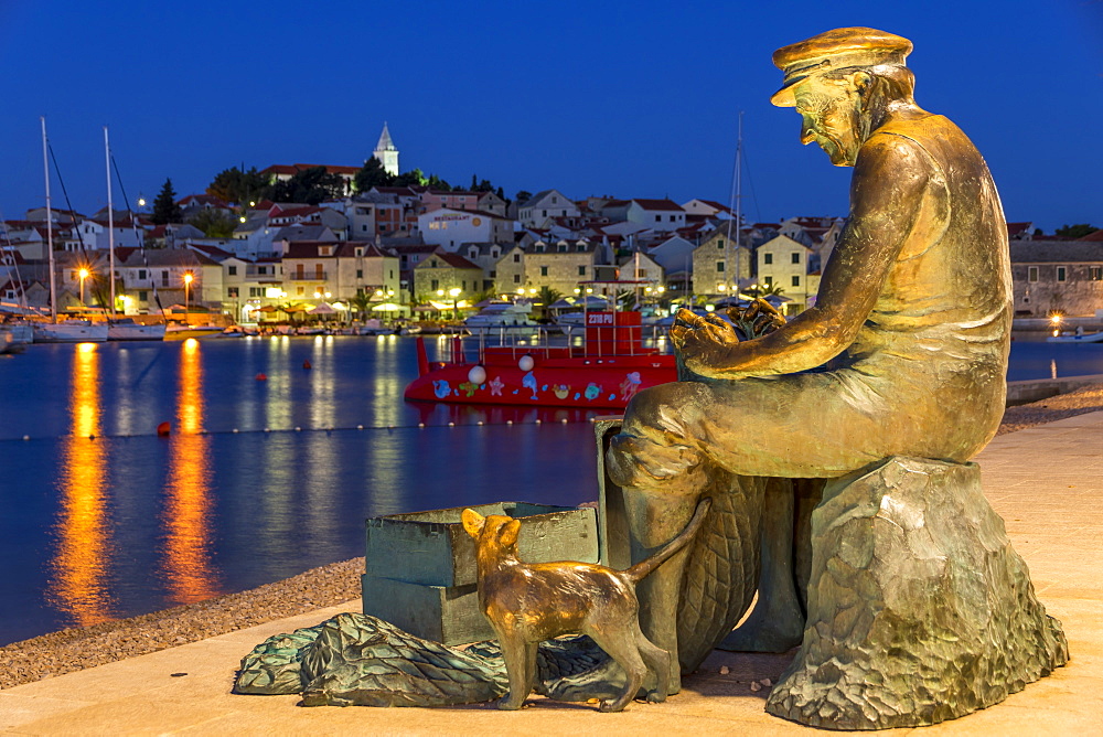 Fisherman statue with view to the old town of Primosten in the background, Croatia, Europe