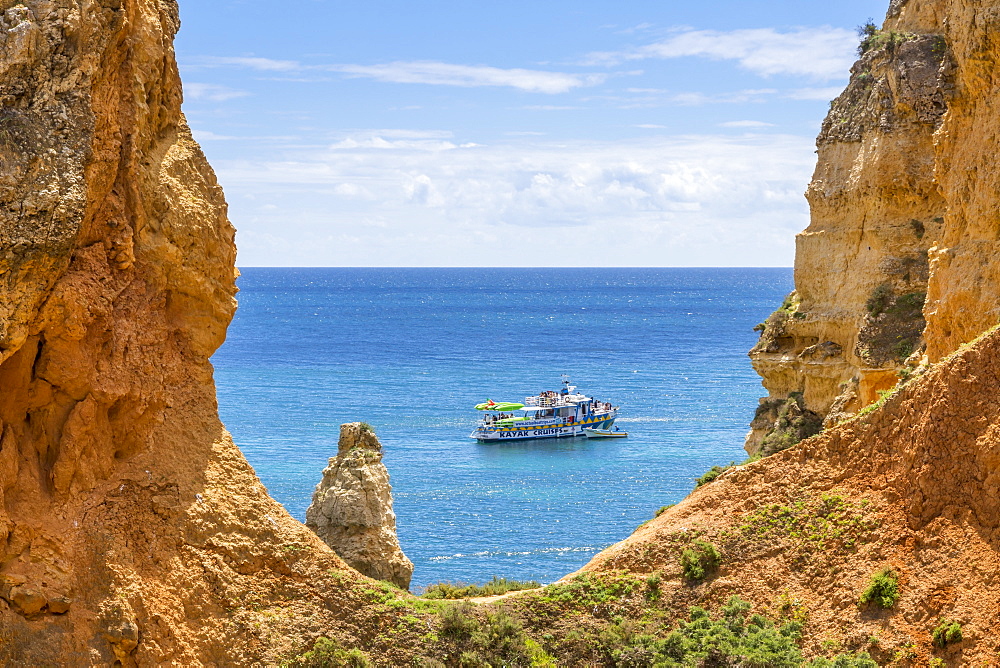 Excursion boat passing the rocky coastline near Lagos, Algarve, Portugal, Europe