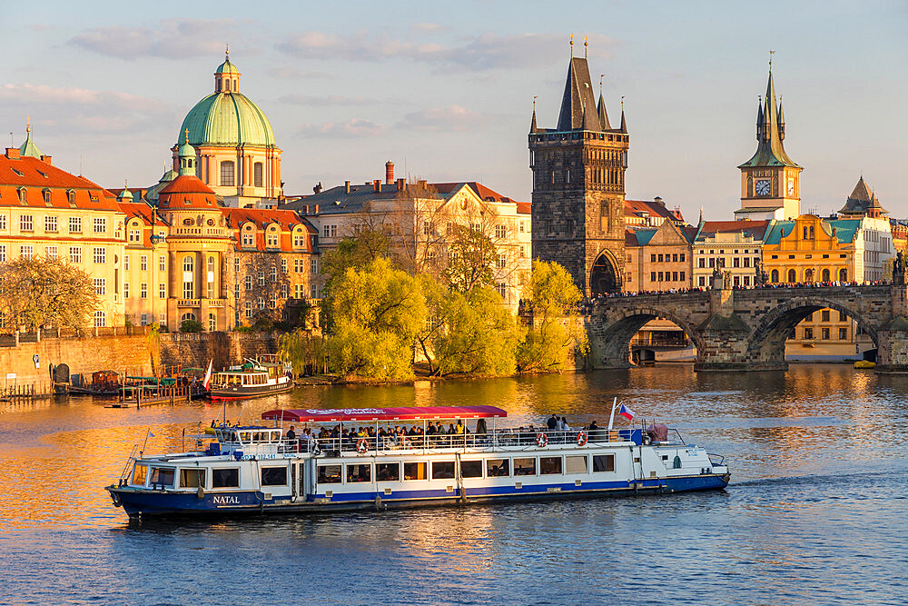 Tourist boat passing Charles Bridge and the Old Town Bridge Tower on Vltava River, Prague, Bohemia, Czech Republic, Europe