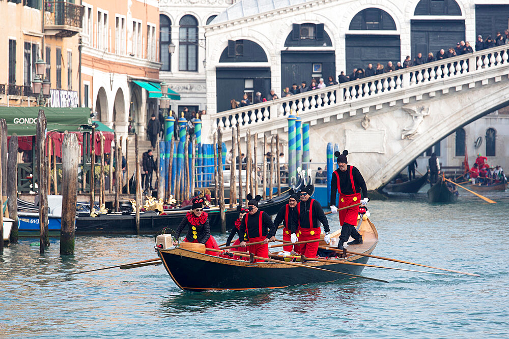 People in Mickey Mouse Venice Carnival costumes, rowing gondola on Grand Canal by Rialto Bridge, Venice, UNESCO World Heritage Site, Veneto, Italy, Europe