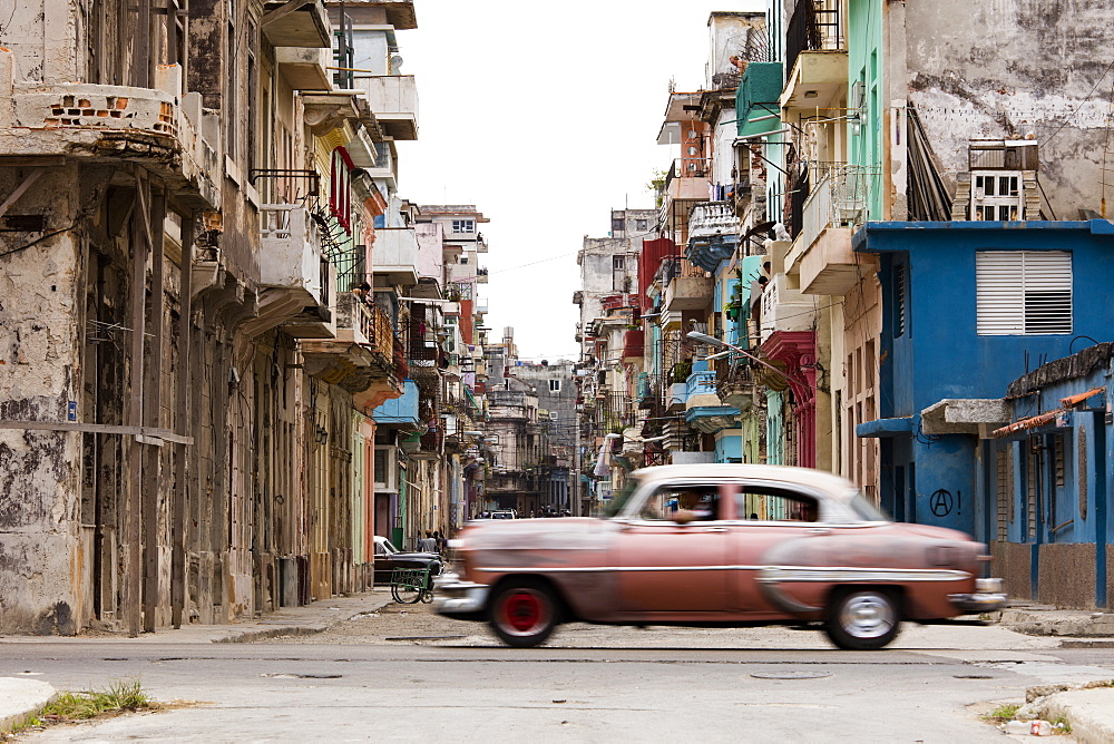 A vintage American car driving across a street in Havana, Cuba, West Indies, Caribbean, Central America