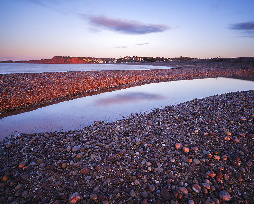 First sunlight falls on Budliegh Salterton with pebbles on the curving beach from Otter Mouth, Budleigh Salterton, Devon, England, United Kingdom, Europe