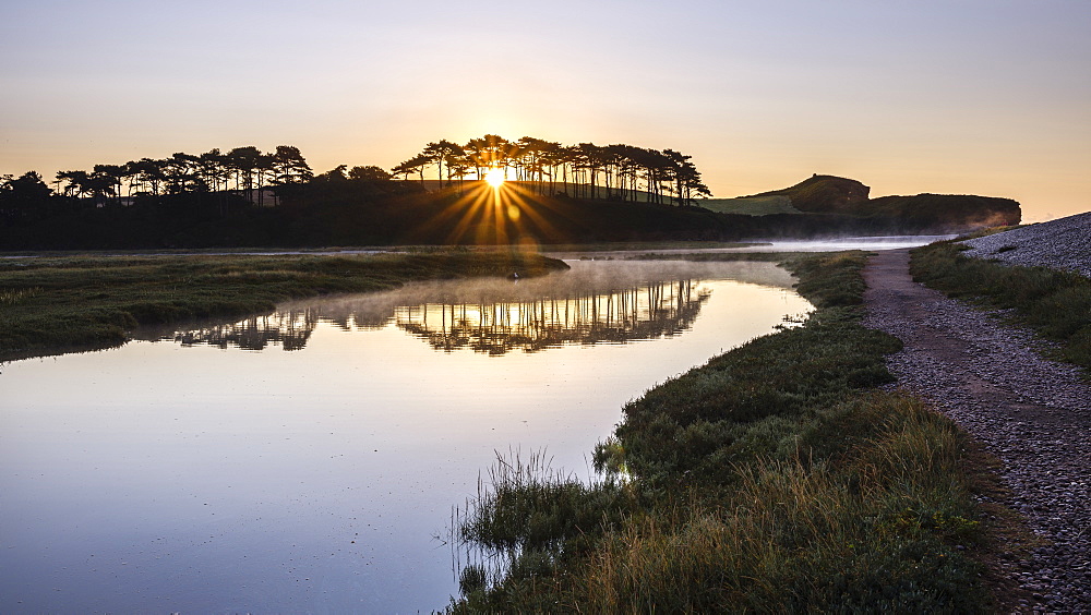 A scenic sunrise with mist and perfect reflections on the River Otter at Budleigh Salterton, Devon, England, United Kingdom, Europe