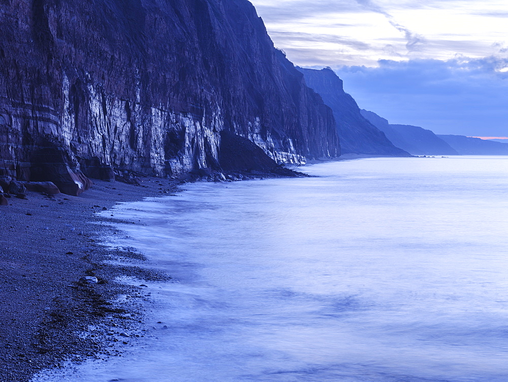 Soft glow of wet rock in pre-dawn twilight on the statuesque Jurassic Coast cliffs at Sidmouth, Devon, England, United Kingdom, Europe