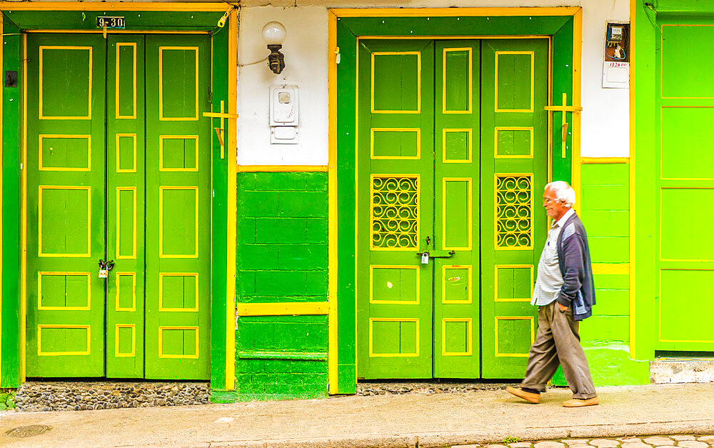 A local man walking past a typically colourful, preserved, colonial building, Jardin, Colombia, South America