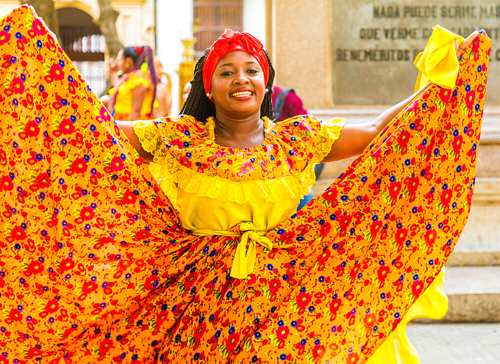 A woman wearing colourful traditional clothing dancing, Cartagena de Indias, Colombia, South America