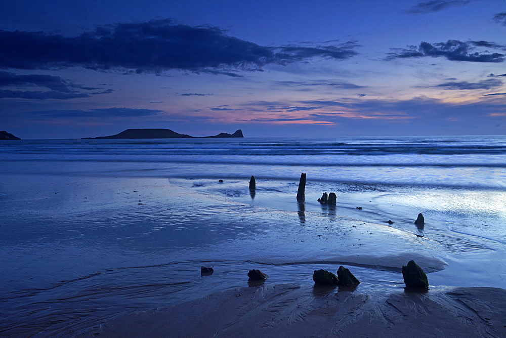 Dusk over the wreck of the Helvetia and Worms Head at Rhossili Bay, Gower, Wales, United Kingdom, Europe