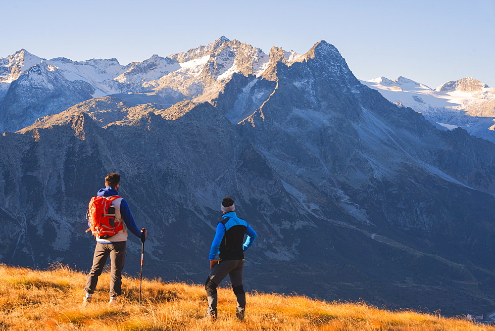 Hikers admiring the mountains in autumn season in Stelvio National Park in Brescia Province, Lombardy, Italy, Europe