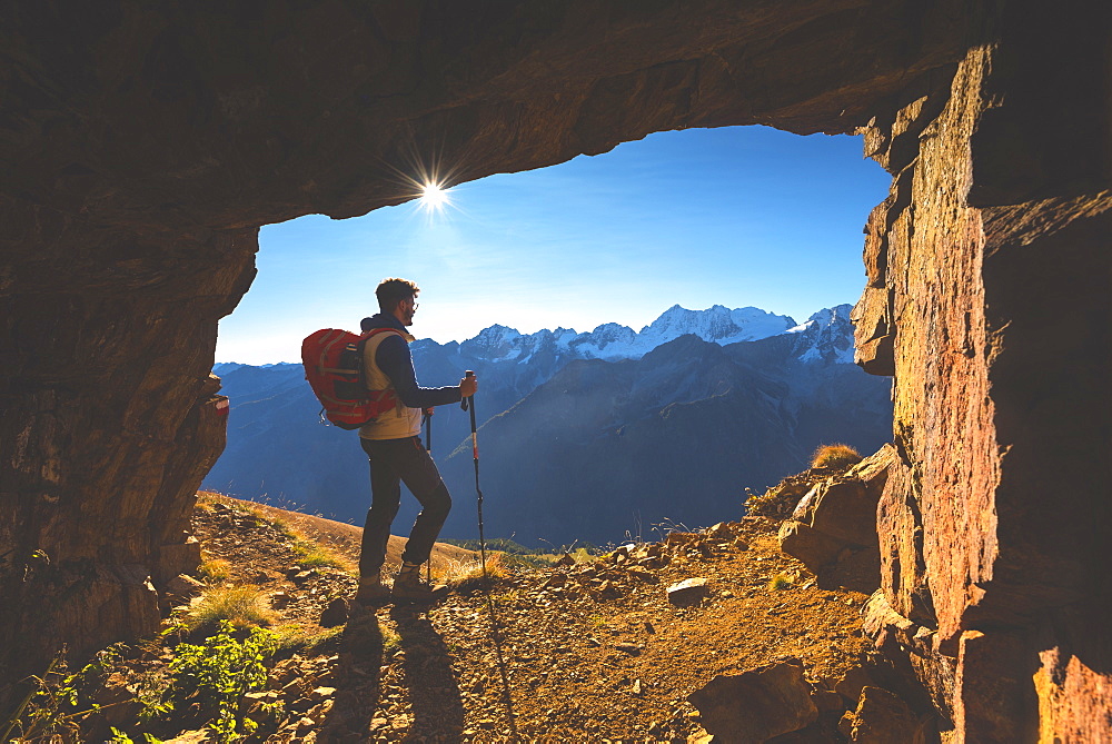 Hiker in a mountain cave in autumn season in Stelvio National Park in Brescia Province, Lombardy, Italy, Europe