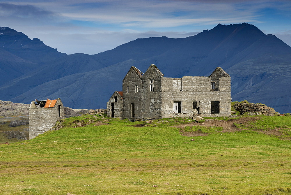 Abandoned farmhouse with mountain backdrop beside the road to Hofn, Eastern Region, Iceland, Polar Regions