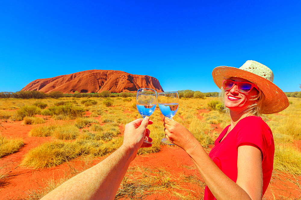 Woman doing cheers at Uluru (Ayers Rock) at sunset in Red Centre, Uluru-Kata Tjuta National Park, UNESCO World Heritage Site, Northern Territory, Australia, Pacific