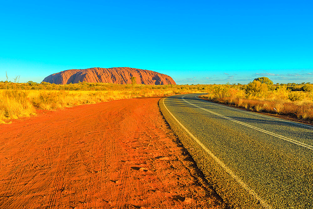 Road leading to Uluru (Ayers Rock) at vibrant color of sunset, Outback, Uluru-Kata Tjuta National Park, UNESCO World Heritage Site, Northern Territory, Australia, Pacific