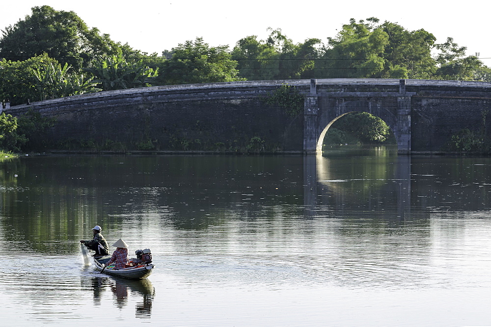 A man and woman fishing from a small boat in the moat around the Citadel in Hue, Vietnam, Indochina, Southeast Asia, Asia