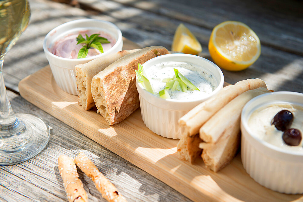 Meze at a Cypriot restaurant of Taramasalata, tzatziki, hummus, pitta bread, lemon and olives accompanied with white wine, Cyprus, Mediterranean, Europe