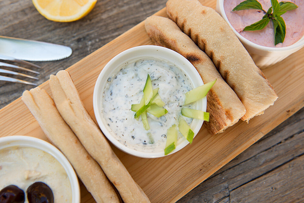 Meze at a Cypriot restaurant of Taramasalata, tzatziki, hummus, pitta bread, lemon and olives accompanied with white wine, Cyprus, Mediterranean, Europe