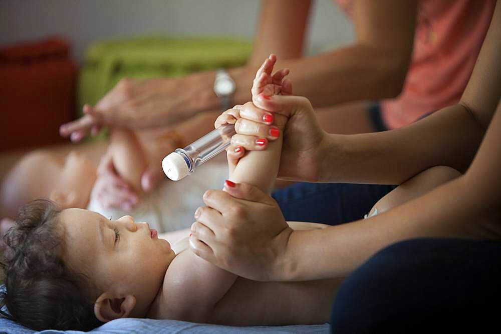 Baby massage lesson with a certified masseur, a young mother learns how to massage her 1-year old son.