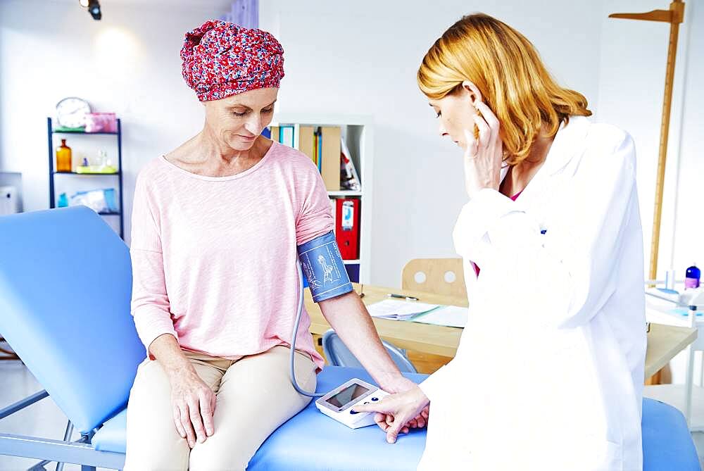 Doctor measuring blood pressure of a woman suffering from cancer.