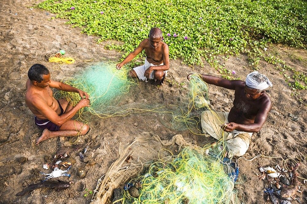 Fishermen mending fishing nets at Kappil Beach, Varkala, Kerala, India