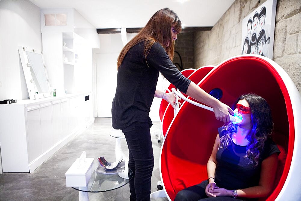 Reportage in a smile bar in Paris, France. Teeth whitening involves applying a whitening paste using a special mouthpiece, then exposing the teeth to a LED lamp which sets off the whitening process.