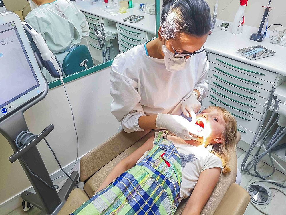 Gloved hands of an orthodontist who inspects the teeth of an 8-year-old girl to correct the bad posture of the jaws and teeth with the installation of braces, France, Europe.