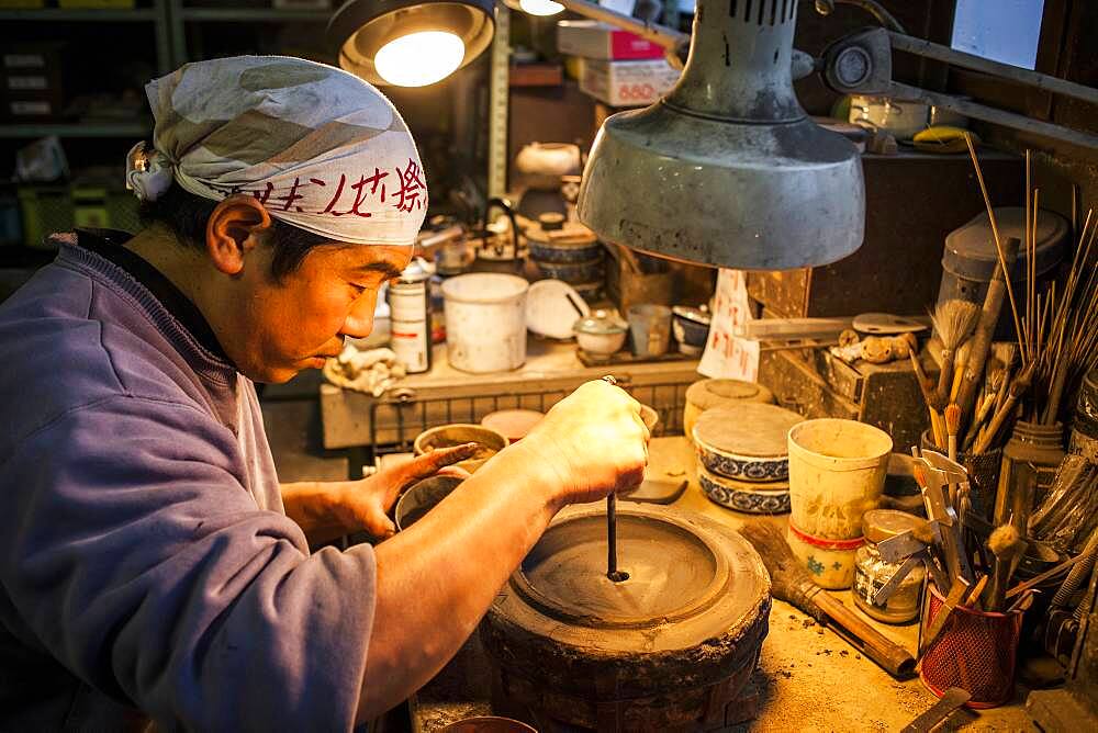 Takahiro Koizumi is making the outer mold of a new design of a iron teapot or tetsubin, nanbu tekki,Workshop of Koizumi family,craftsmen since 1659, Morioka, Iwate Prefecture, Japan