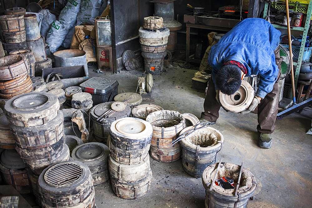 Kohei ishimori checks that the outer molds are properly cooked, to resist the molten iron and make a iron teapot or tetsubin, nanbu tekki,Workshop of Koizumi family,craftsmen since 1659, Morioka, Iwate Prefecture, Japan