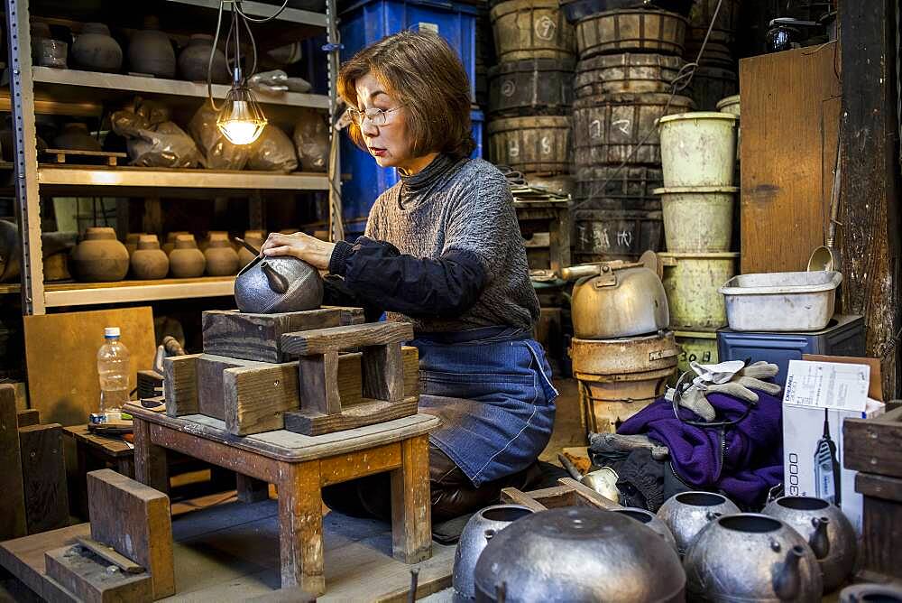 Morihisa Suzuki  is putting the finishing touches at iron teapot or tetsubin, the only woman who has made teapots in the nearly 400 years of history that has molten iron crafts in Iwate, in Workshop of Morihisha Suzuki,craftsmen since 1625, nanbu tekki, Morioka, Iwate Prefecture, Japan