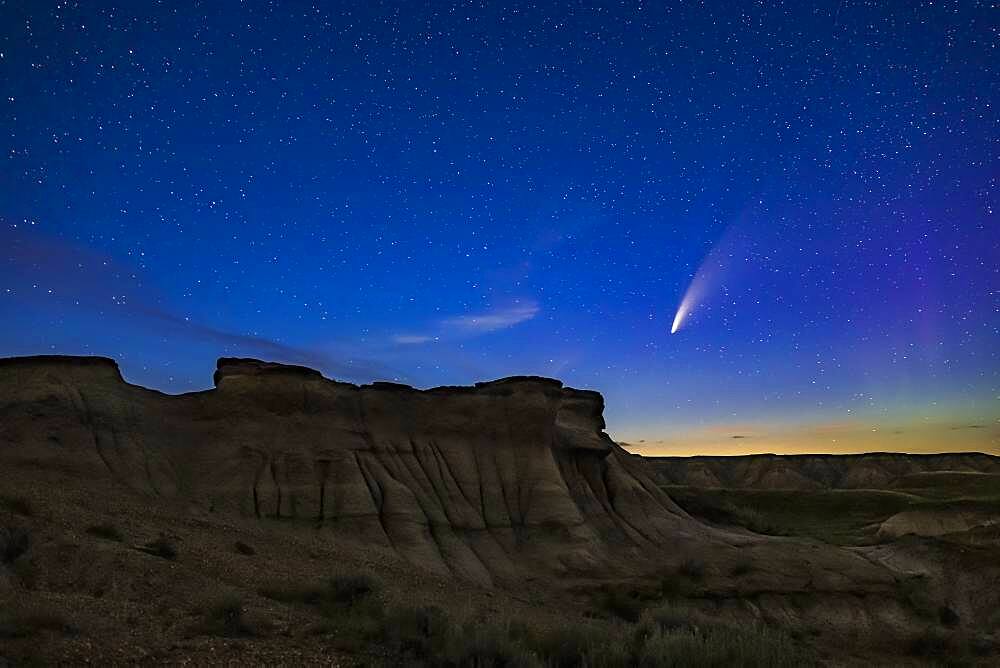 Comet NEOWISE (C/2020 F3) over some of the eroded hoodoo formations at Dinosaur Provincial Park, Alberta, July 14-15, 2020.  A faint aurora is at right. The foreground is lit by starlight only; there was no light painting employed here.