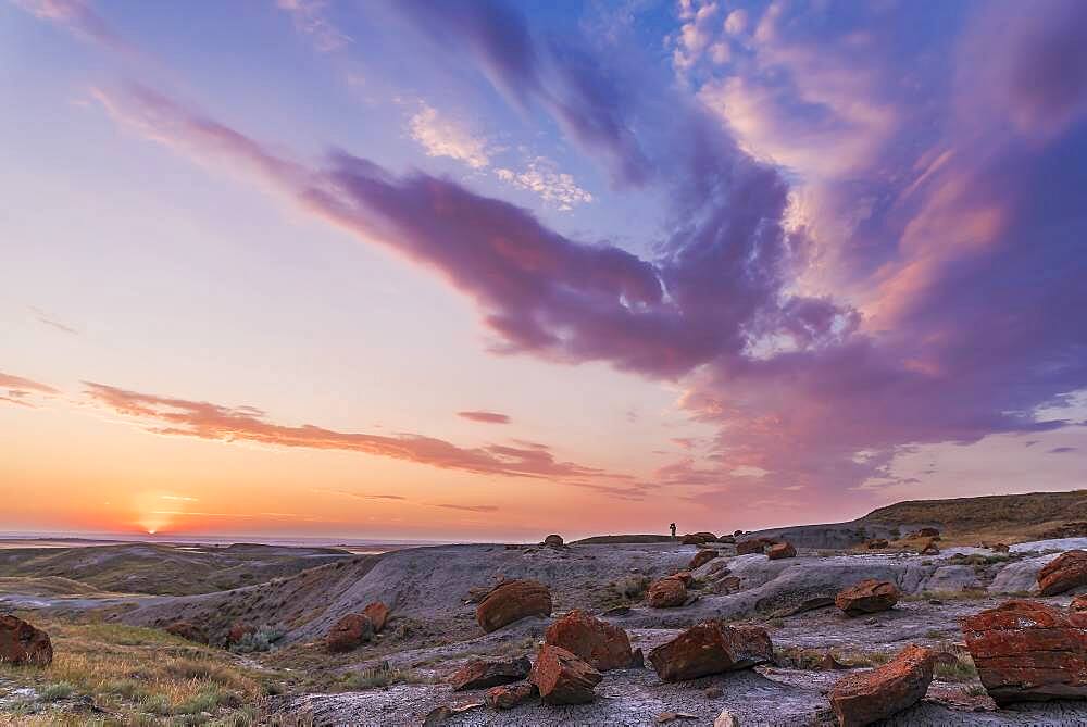 A particularly colourful sunset at the Red Rock Coulee Natural Area in southeast Alberta, with a lone figure silhouetted against the sky.