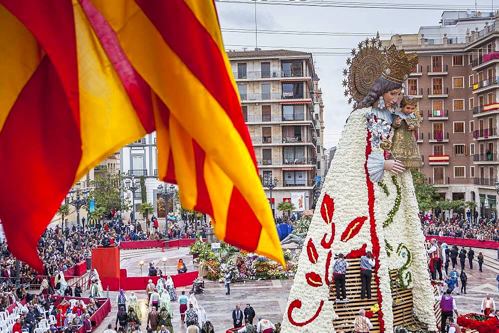 Men placing flower offerings on large wooden replica statue of Virgen de los Desamparados, Fallas festival,Plaza de la Virgen square,Valencia