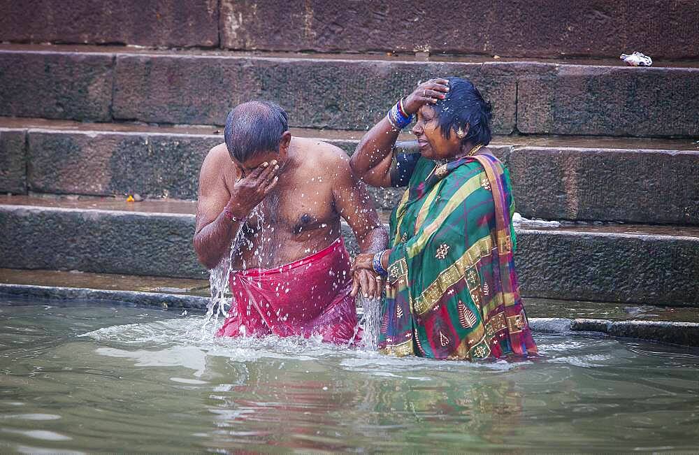 Pilgrims praying and bathing, in the ghats of Ganges river, Varanasi, Uttar Pradesh, India.