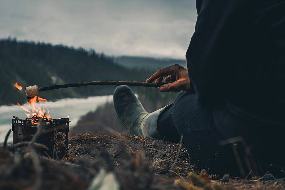 Woman roasting a marshmallow on a cold day early in the year. Yukon Territory, Canada