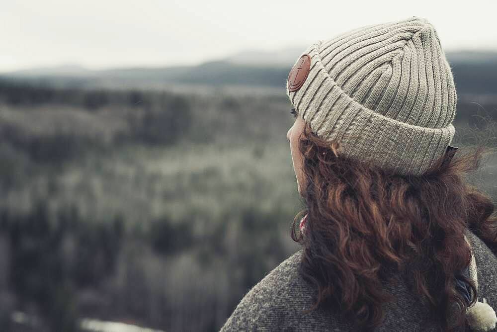 A young Woman lets her view wander across a vast valley. Yukon Territory, Canada