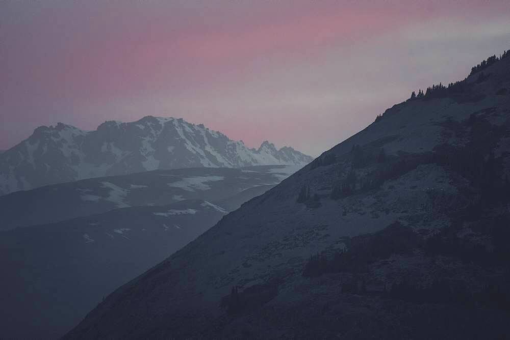 The sky is glowing softly as the sun sets behind the mountains of the Kluane National Park. Yukon Territory, Canada