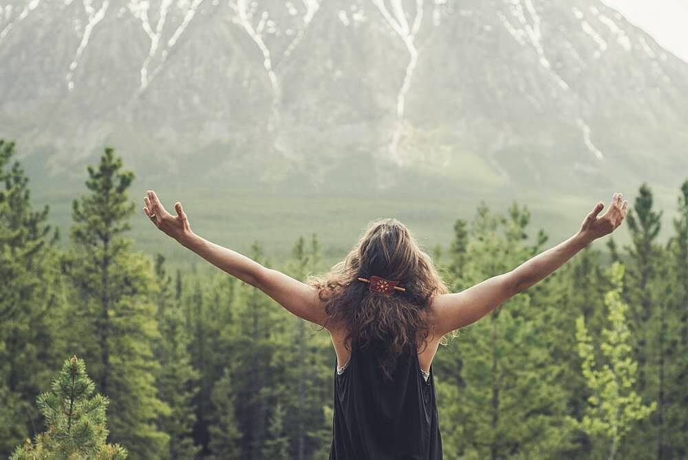 A young woman embraces nature with open arms. Yukon Territory, Canada