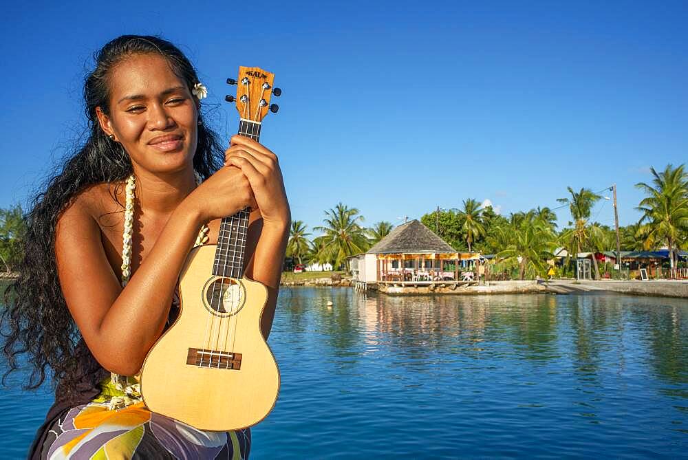 Beautiful local woman playing ukulele in Rangiroa beach, Tuamotu Islands, French Polynesia, South Pacific.