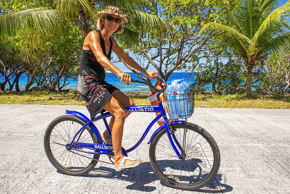 Tourist girl with a bike in Fakarava,  Tuamotus Archipelago French Polynesia, Tuamotu Islands, South Pacific.