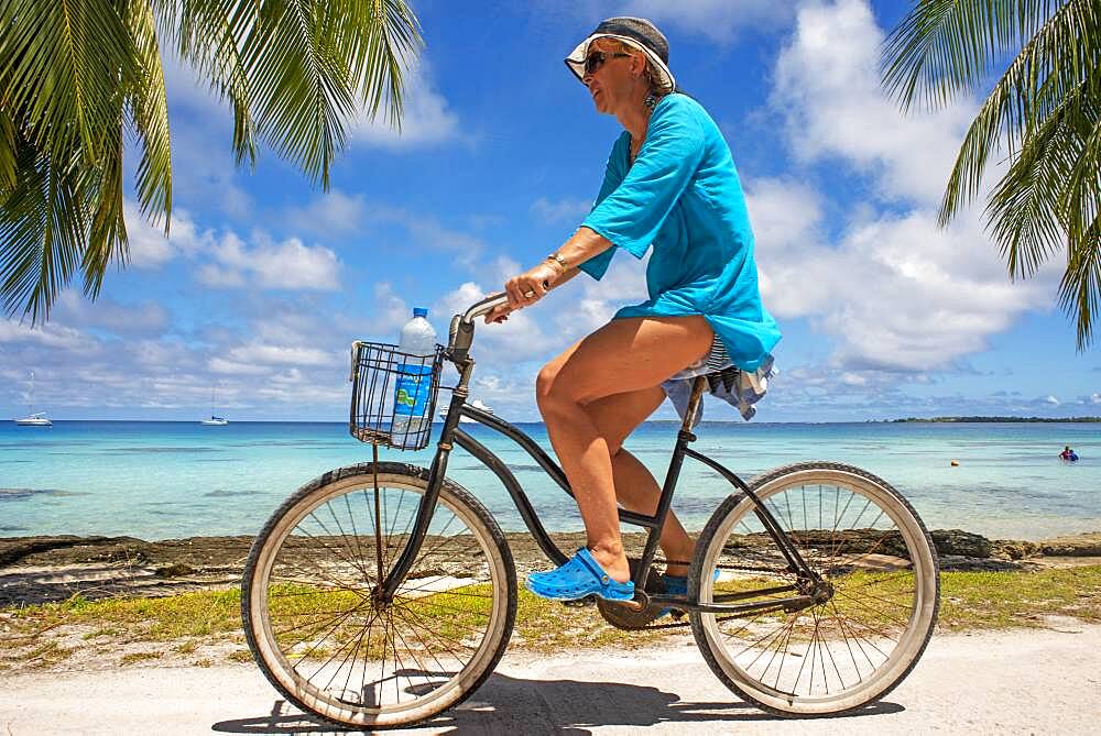 Tourist girl with a bike in Fakarava,  Tuamotus Archipelago French Polynesia, Tuamotu Islands, South Pacific.