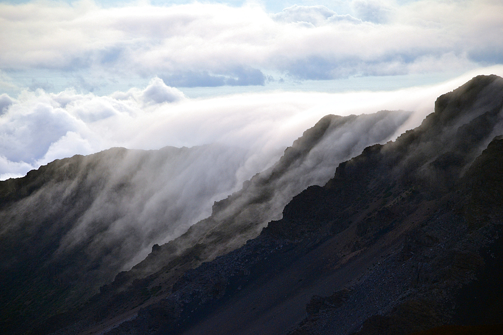 Clouds over a mountain edge at the summit of Haleakala volcano during sunrise, Maui, Hawaii, USA