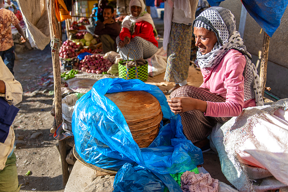 Woman smiling as she prepares Injera or Ethiopian flatbread at outdoor market, Deber Berhan, Ethiopia