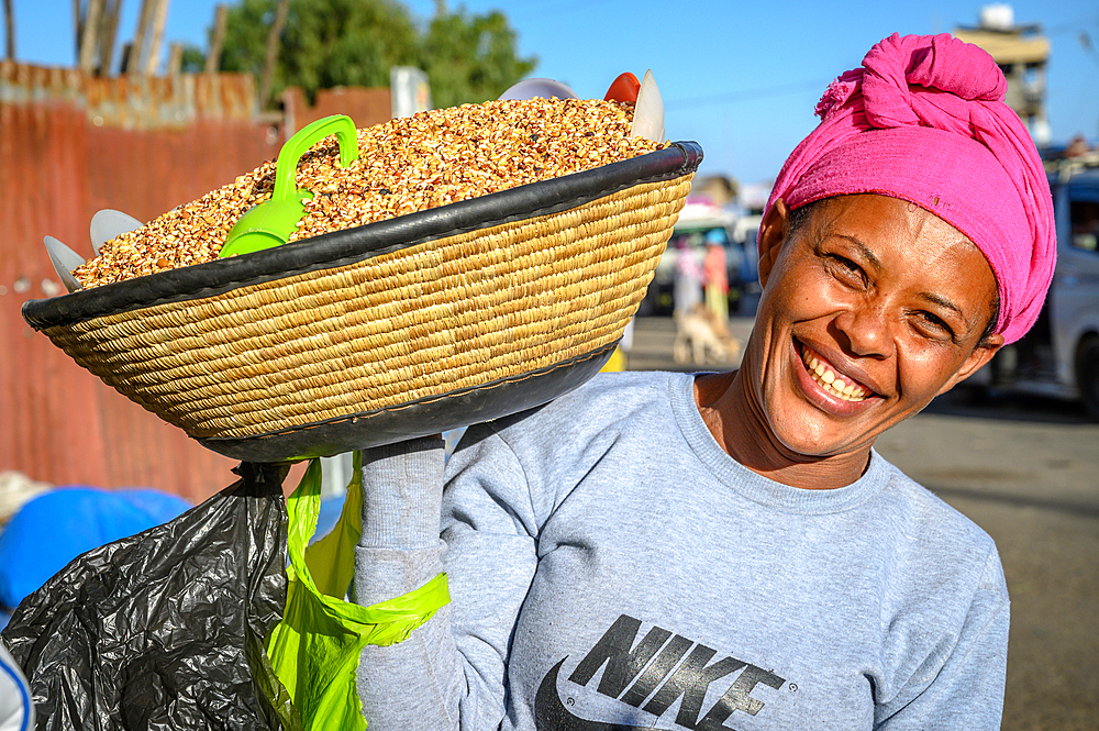 Smiling woman carrying basket full of Kolo or roasted barley on her shoulder, Debre Berhan, Ethiopia