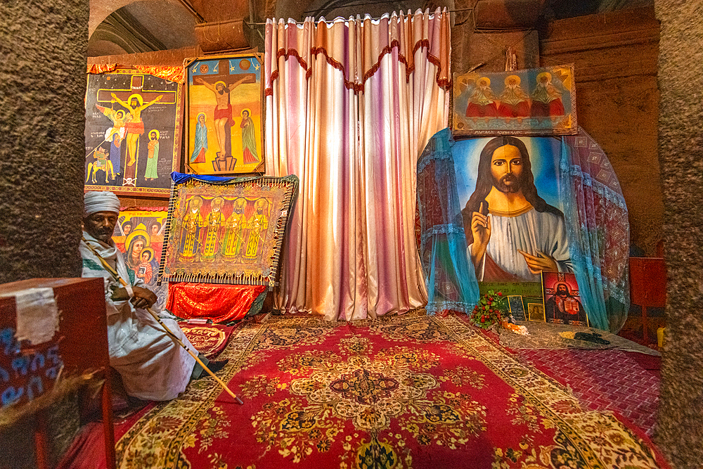 A man sits near a collection of Christian artwork within the church of Bet Medhane Alem (Church of the World Savior) in Lalibela, Ethiopia