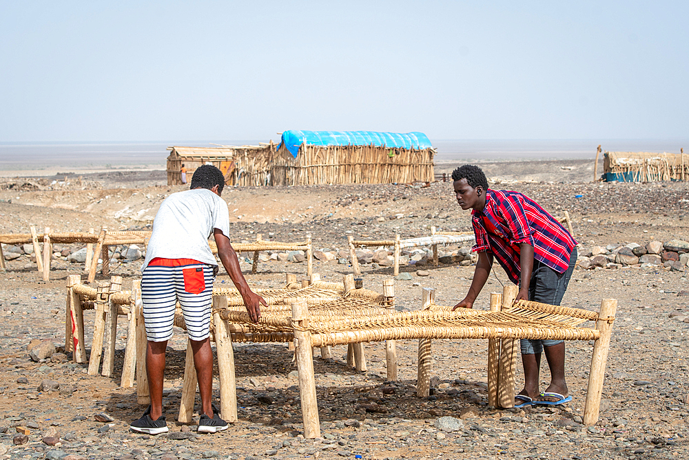 Two men set up cots in a salt miner camp in the Danakil Depression, Ethiopia