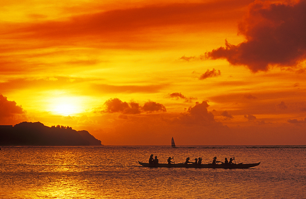 Guam, Micronesia: outrigger canoe paddlers at sunset at Tumon Bay resort area.