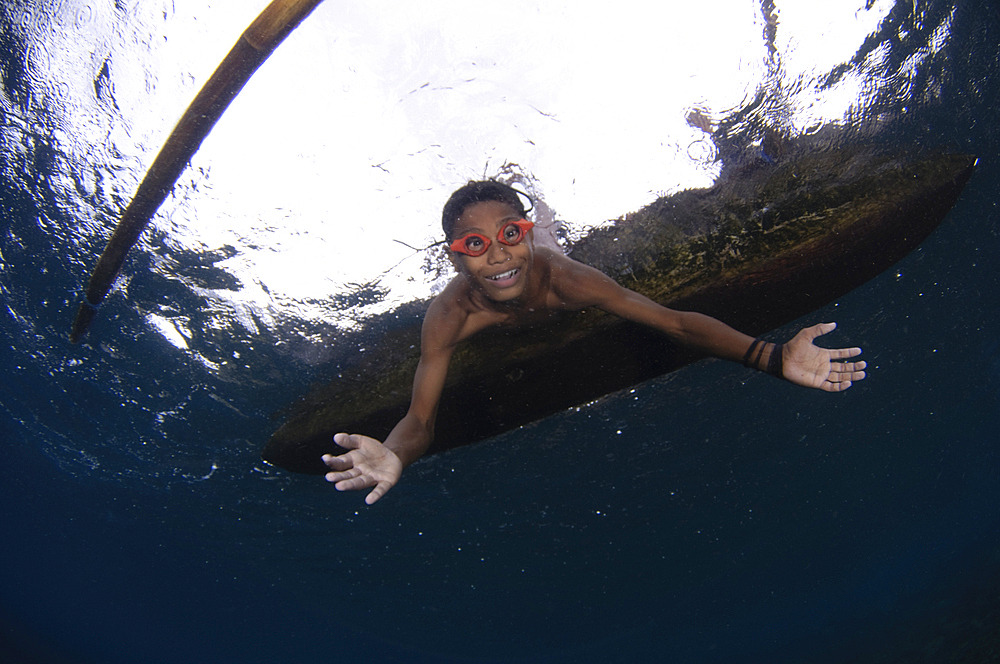 Local children swimming from small outrigger canoes using home made goggles, Alor Island, Nusa Tenggara, Indonesia, Pacific Ocean