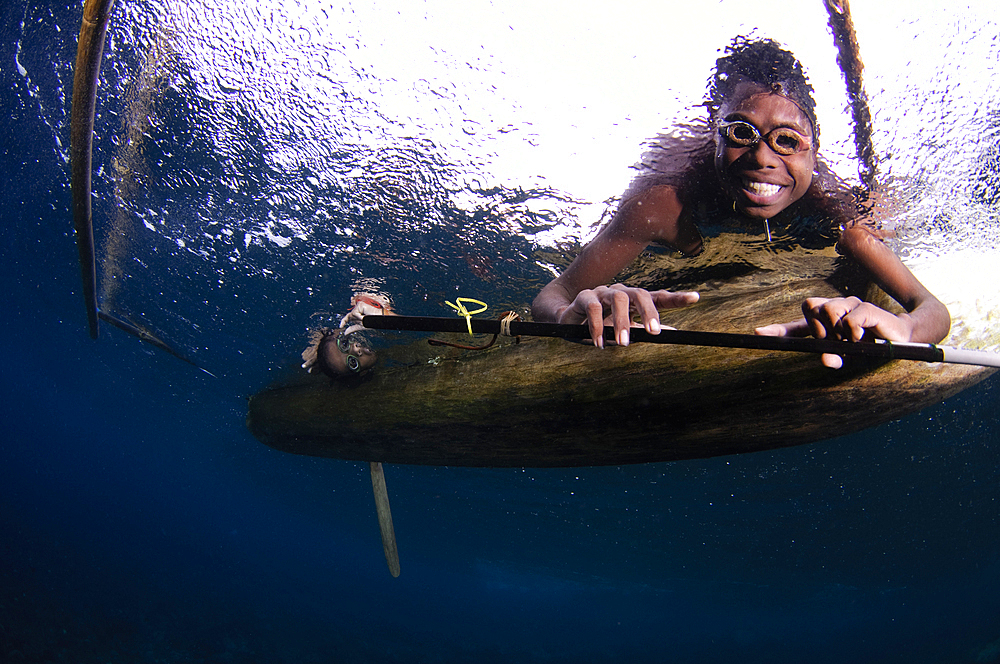 Local children swimming from small outrigger canoes using home made goggles, Alor Island, Nusa Tenggara, Indonesia, Pacific Ocean