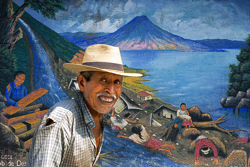 Local man walking in front of a wall panting in San Juan La Laguna, Solol√°, Guatemala. Traditional mayan painting art Santiago Atitlan, lake Atitlan, Guatemala.