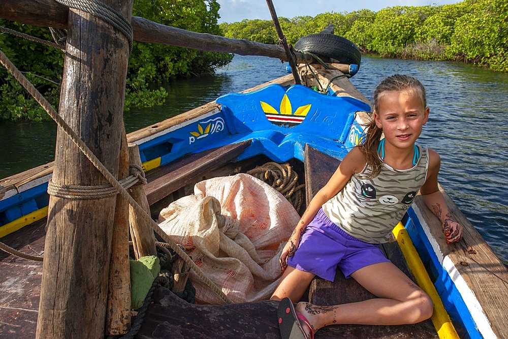 European tourists girl in a dhow sailing through Makanda Channel, Lamu archipelago, Kenya. Red mangroves along coastline of Manda Island